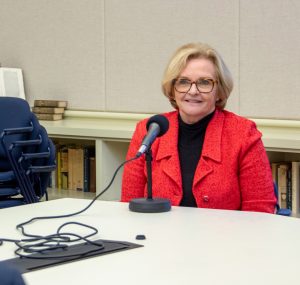 Claire McCaskill sits at a microphone in the Seminar Room of Hyde Hall, recording a podcast.