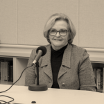 Claire McCaskill sits at a microphone in the Seminar Room of Hyde Hall, recording a podcast.