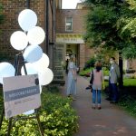 An easel holds blue and white balloons and a sign reading “Welcome Faculty” outside of Hyde Hall.