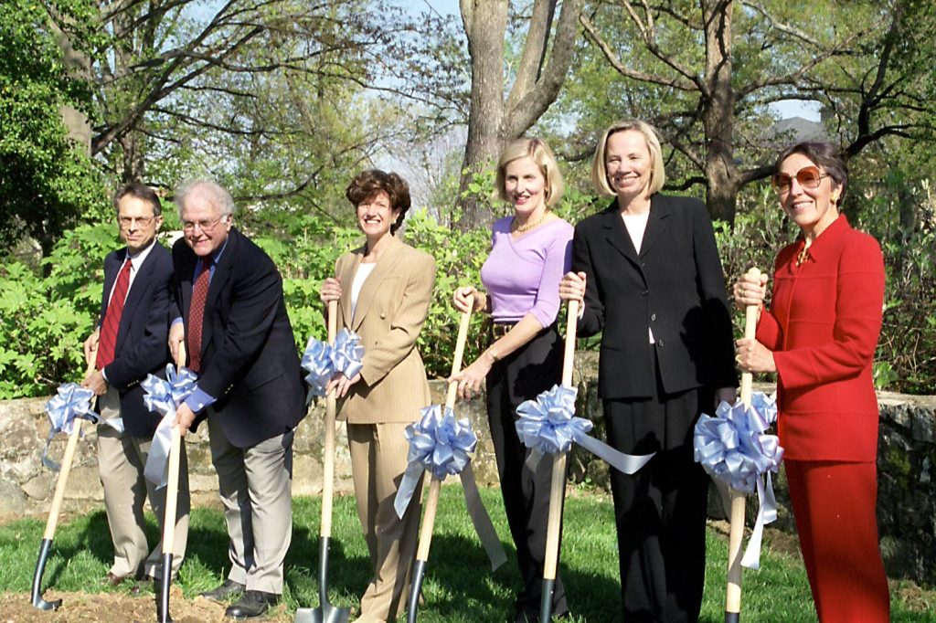 Six people, including Ruel Tyson, Barbara Hyde, Dee Schwab and Beck Pardue, hold shovels with blue ribbons attached to them, pose at the groundbreaking for Hyde Hall on March 31, 2000.