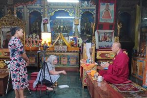  Lauren sits on the floor interviewing the resident monk at Deva Dharma Mahavihar, a Buddhist monastery located in front of the stupa.