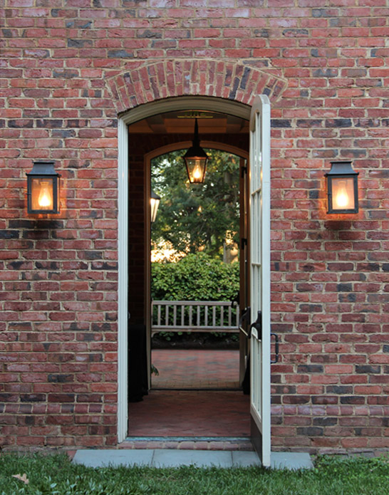Lanterns are lit on either side of a door peaking across the Fellows Gallery into the courtyard of Hyde Hall.