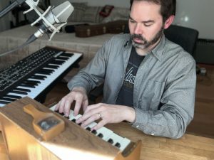 Lee Weisert composes on a toy piano, with a full-size piano next to him.